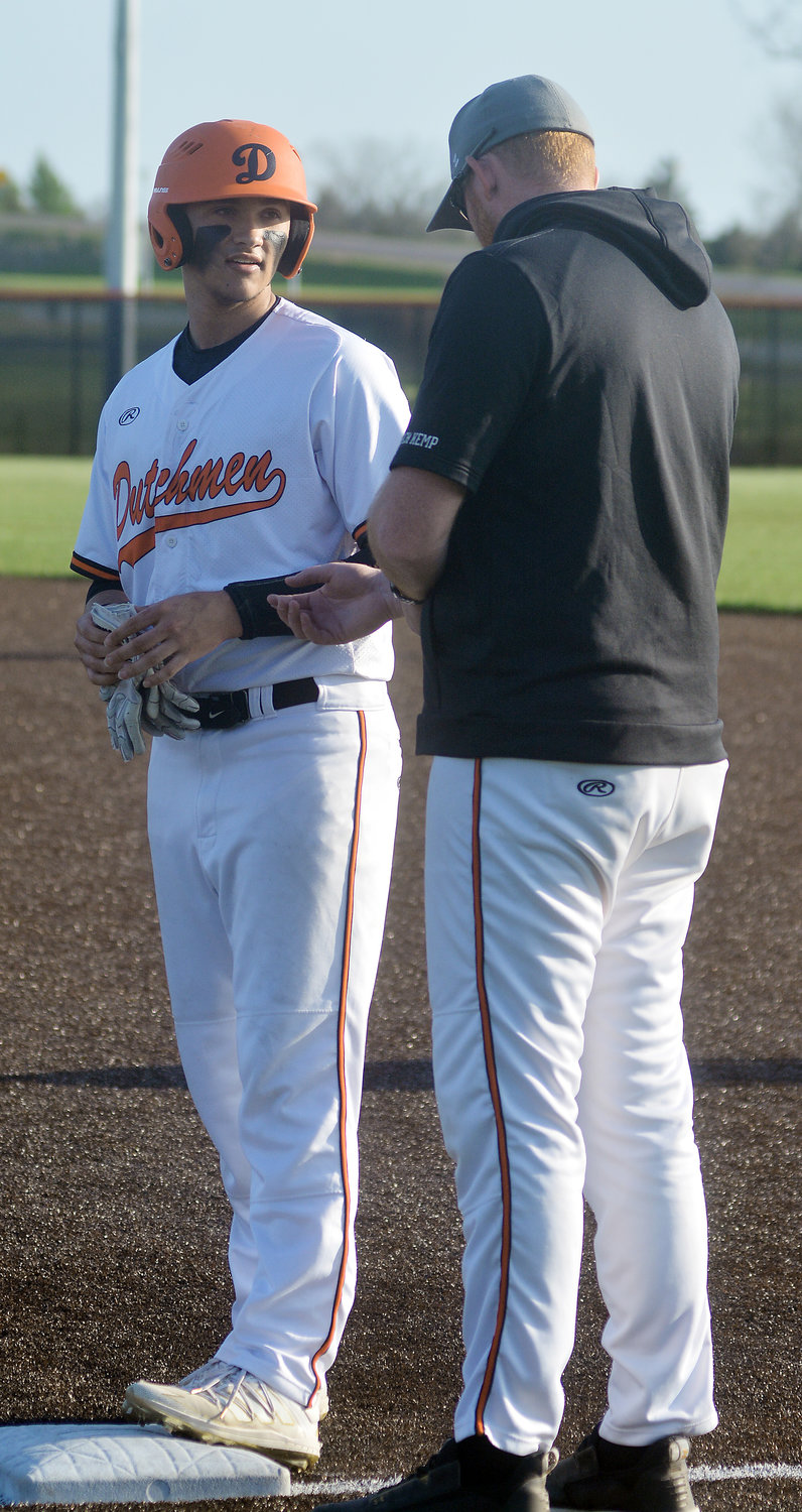Gavin Loague (far left) converses with assistant coach Steven Kemp after safely reaching first base during his senior season. Kemp was recently hired to replace former Dutchmen head baseball coach Tyler Ahring who decided to step away to devote more time to his family.